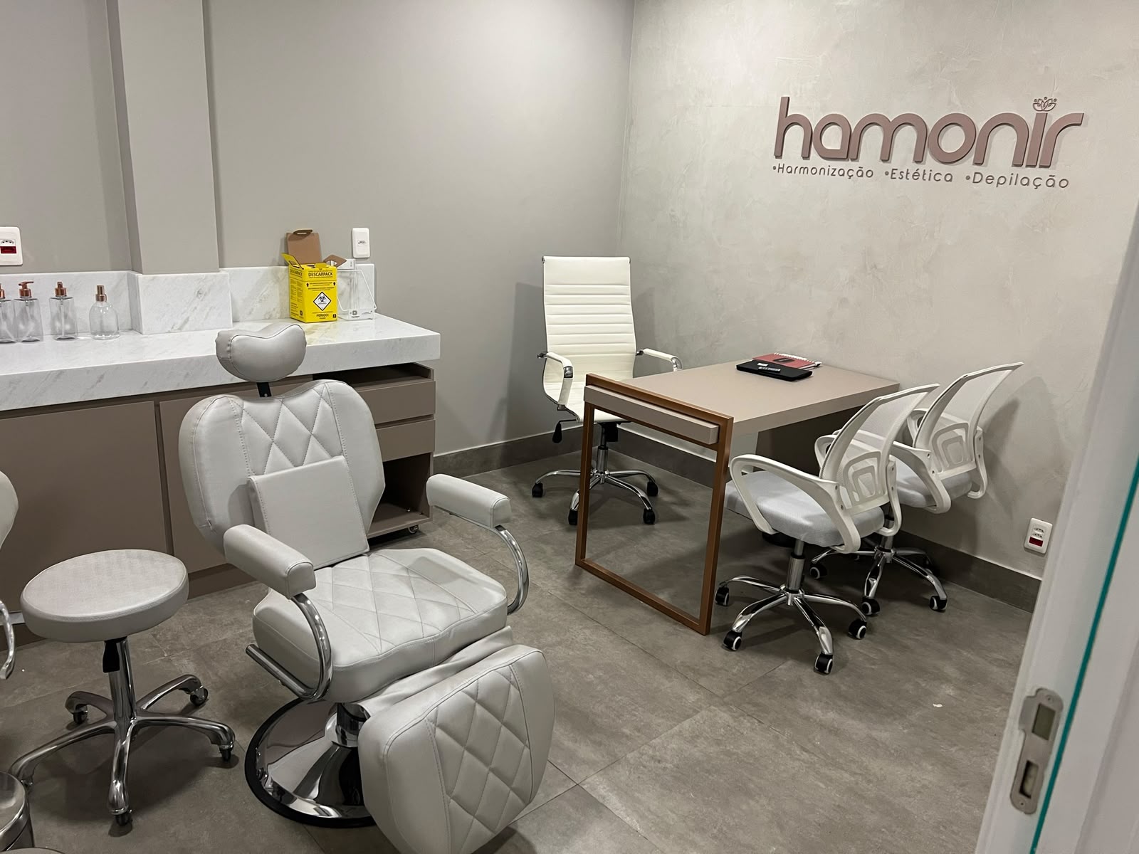 Sala de atendimento da Hamonir com cadeira estética e logo na parede